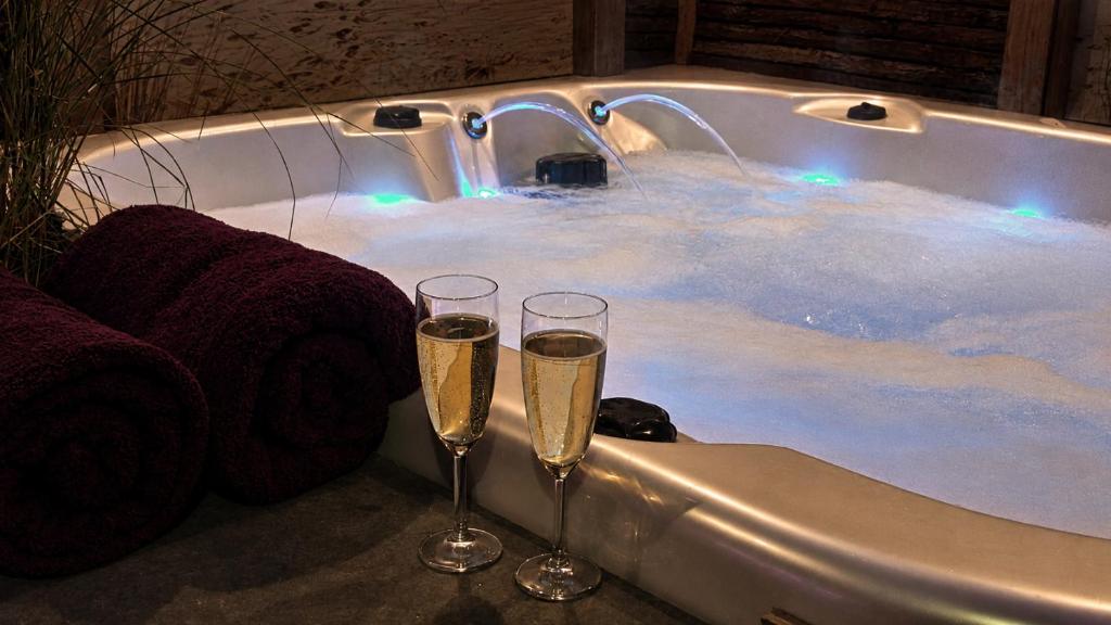 two glasses of champagne in front of a bath tub at Zeeuws Ontspannen - Privé Wellness & Suites in Middelburg