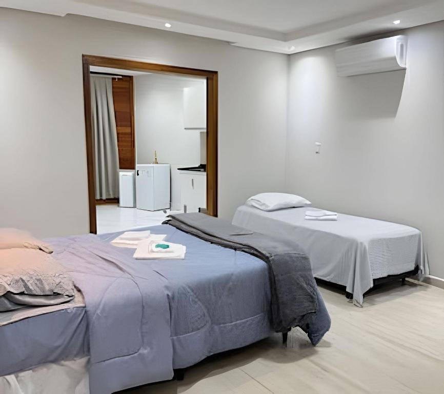 a bedroom with two beds and a kitchen in it at Lady Estúdio - Hotel + café em Extrema MG in Extrema