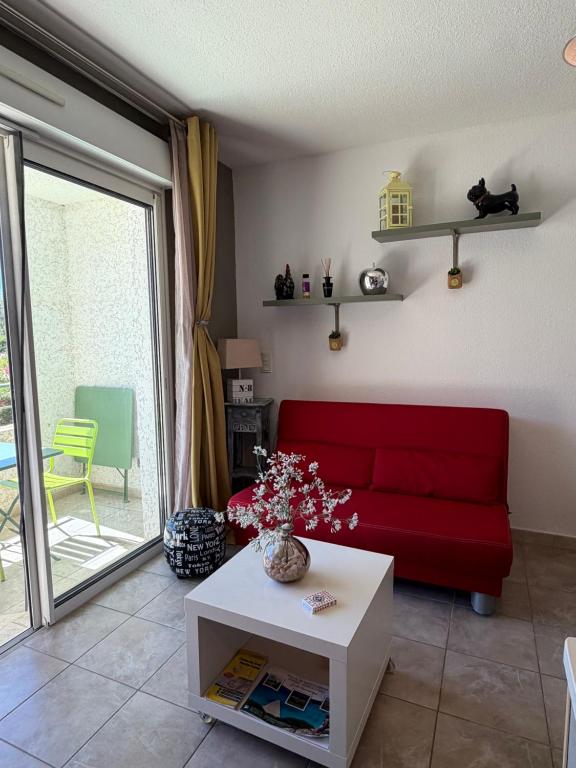 a living room with a red couch and a table at Studio en plein cœur de Saint Florent in Saint-Florent