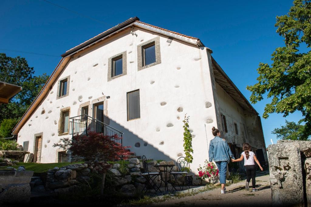 a man and woman walking past a building at Maison d hôtes Les Bruyères in Bonvillars