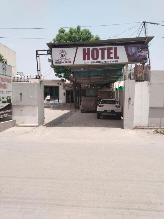 a hotel with a car parked under a sign at Shelton Royal Hotel in Multan
