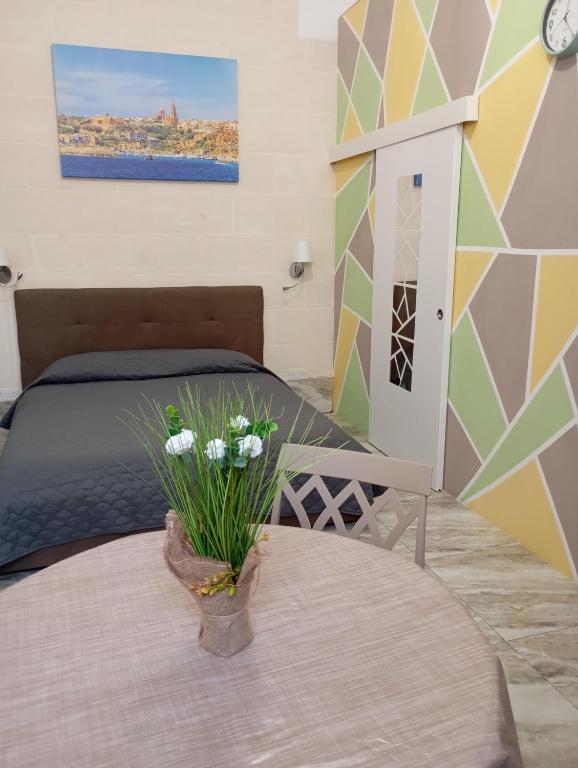 a bedroom with a bed and a table with flowers on it at NJ Stay Gozo in Għajnsielem