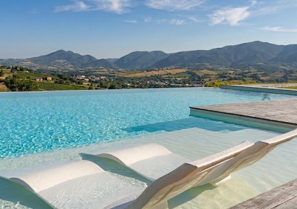 a swimming pool with two lounge chairs in the water at Serre Alte Landscape Luxury Rooms in Matelica