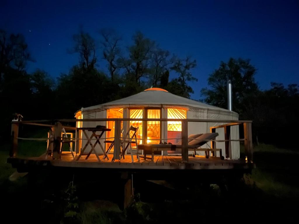 a gazebo with a table and chairs on a deck at night at Káli Jurta in Tapolca