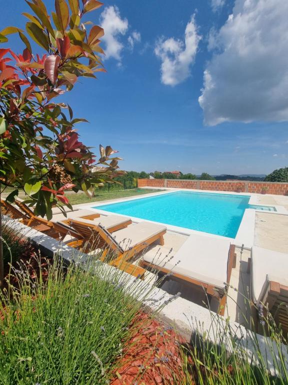a swimming pool with chaise lounges next to a resort at Vikendica BeeLux in Banja Luka