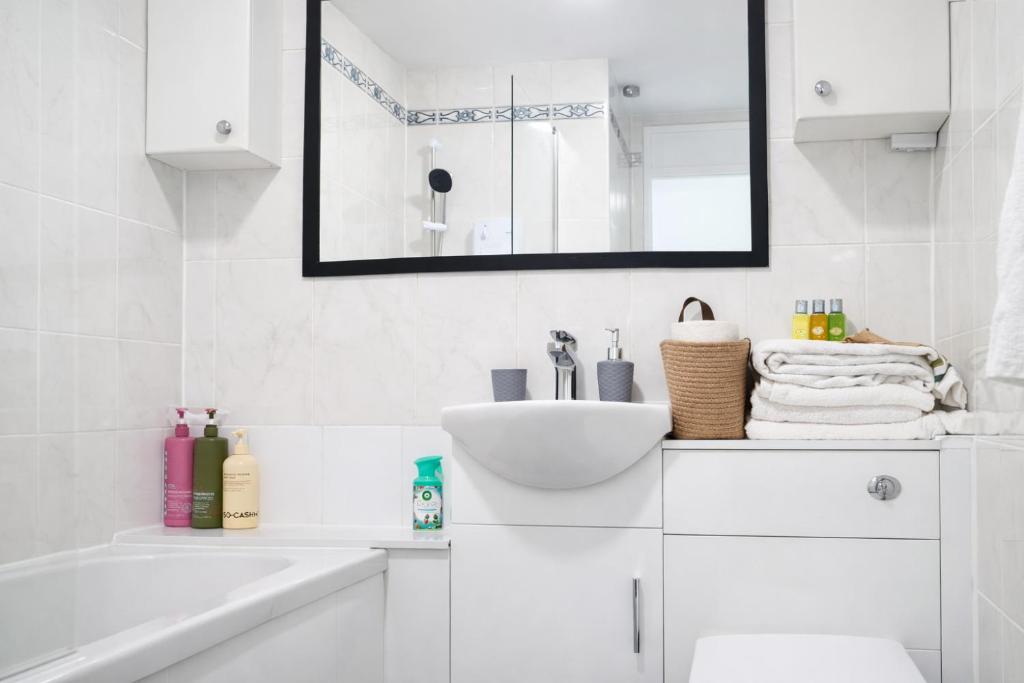 a white bathroom with a sink and a mirror at Onyx Place Spacious 3BR Home l Fast London Commute l Parking in North Ockendon