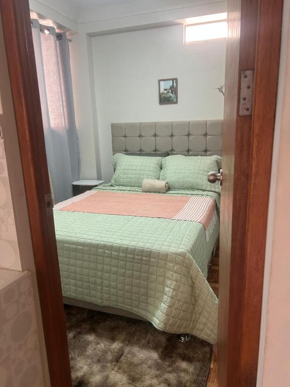 a small bedroom with a bed with a green comforter at Wiracocha Apartments #1 in Cusco