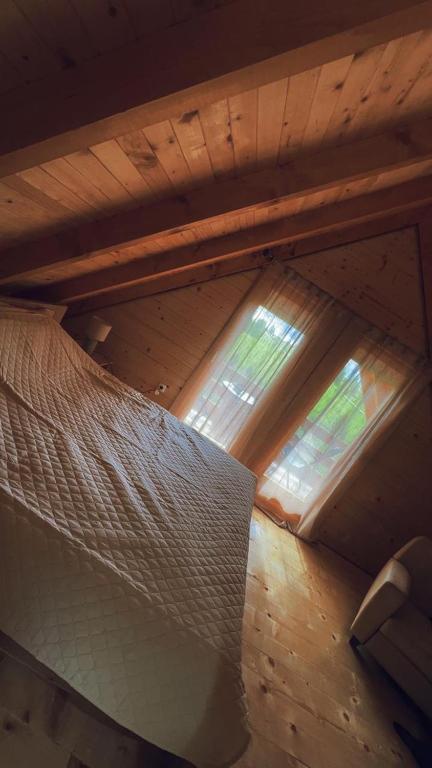 a attic room with a bed and two windows at Camp Birch Forest in Pljevlja