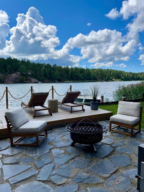 a group of chairs sitting on a wooden deck next to a lake at Paraisten Helmi in Lönäs