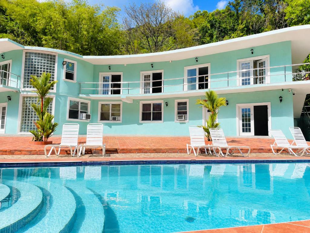 a house with a swimming pool and white chairs at Torraille Waterfall Villas in Soufrière