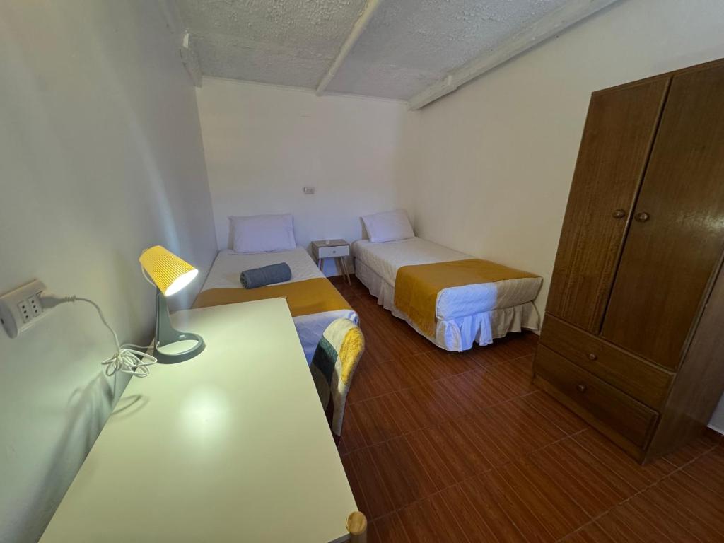 a room with two beds and a table and a cabinet at Hotel Turi Atacama in San Pedro de Atacama