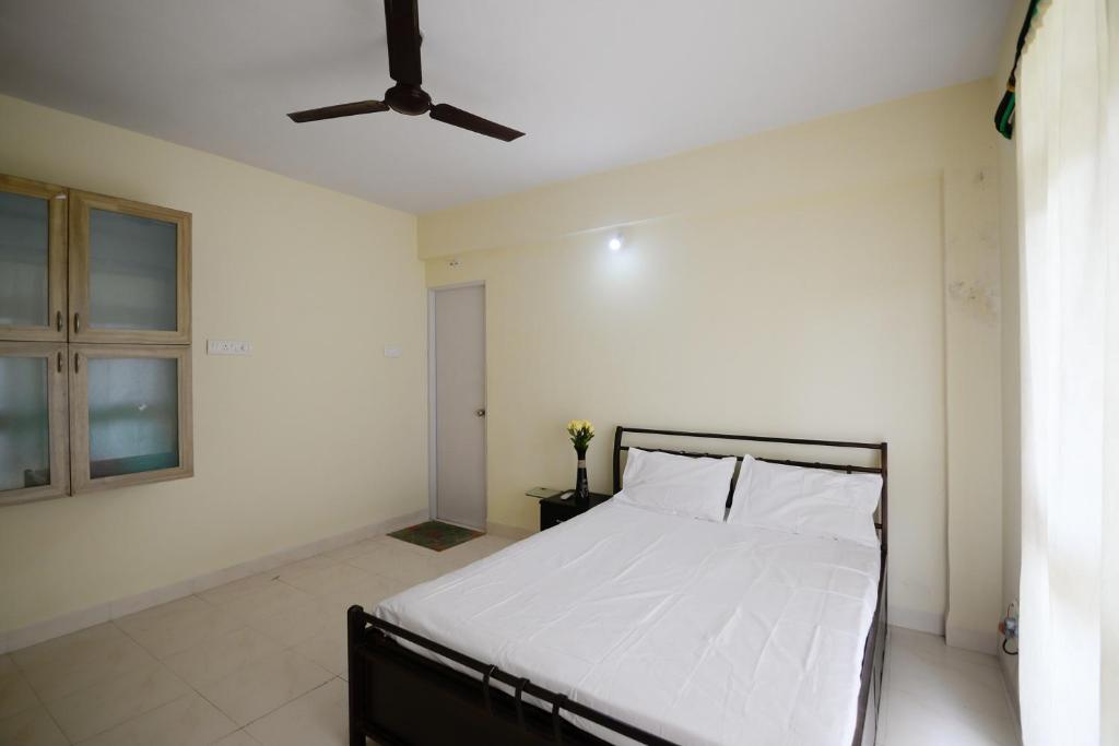 1 dormitorio con cama con sábanas blancas y techo en Sunshine Park Homes - Benaulim at Micon, en Benaulim
