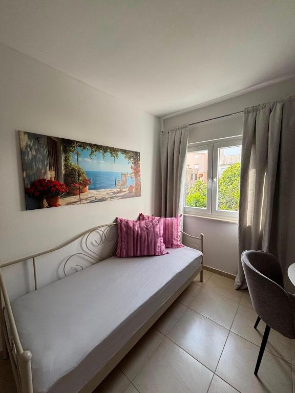 a bed with pink pillows in a room with a window at Apartmani Znaor in Baška Voda