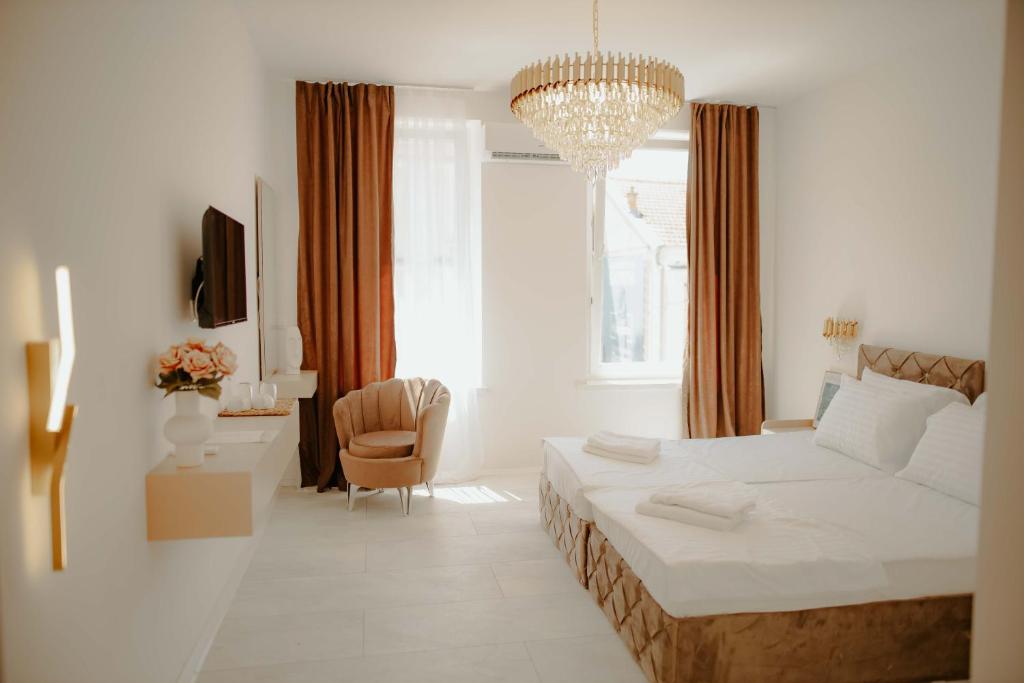 a white bedroom with a bed and a chair at Kiranovi Premium Stay in Bitola
