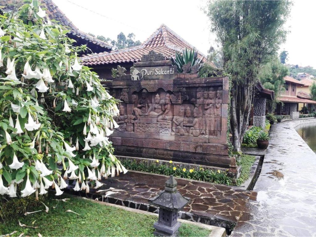 una pared de piedra con una estatua delante de un edificio en Puri Sakanti Nature Family Resort, en Ciwidey