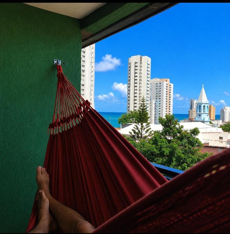 a person laying in a hammock overlooking the city at Quarto triplo em Petrópolis in Natal