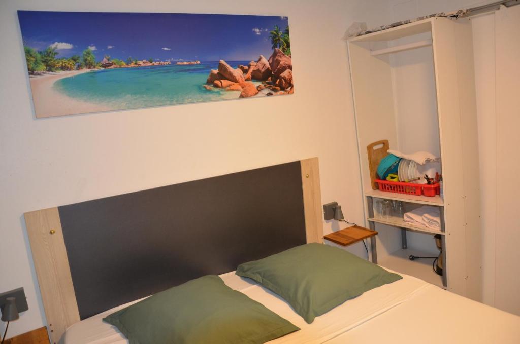 a bedroom with a bed and a picture of a beach at L'évasion Maracuja in Gros-Morne