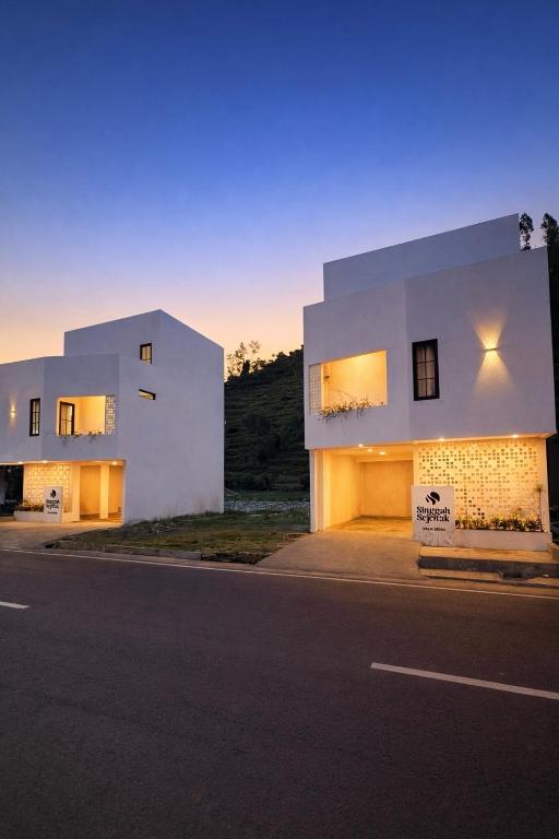 a white house with a sign on the side of a street at Singgah Sejenak Dieng in Diyeng