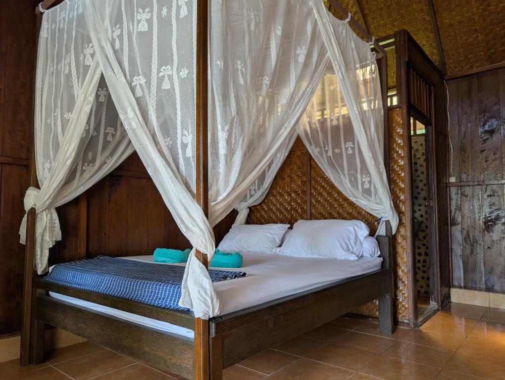 a bed in a room with a canopy at Fadhila Cottages Togean Dive Resort in Katupa