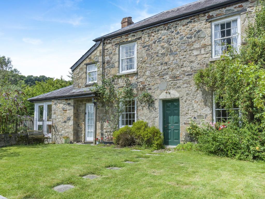 ein altes Steinhaus mit einer grünen Tür in der Unterkunft Primula House in Sticklepath