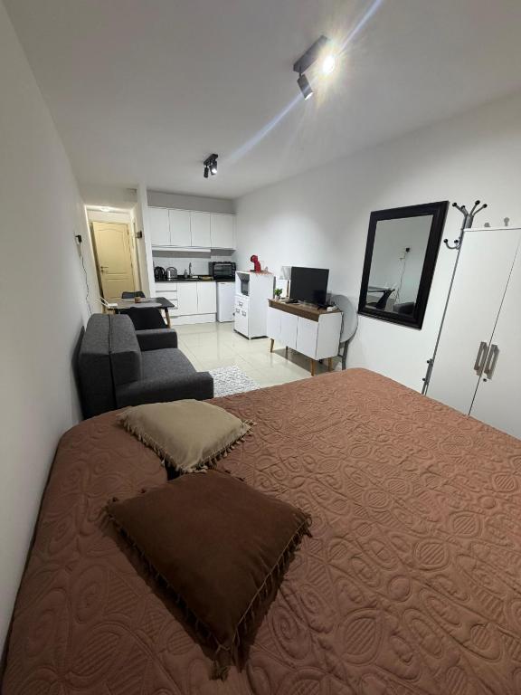 a bedroom with a bed and a couch and a kitchen at Monoambiente como en casa in Montevideo