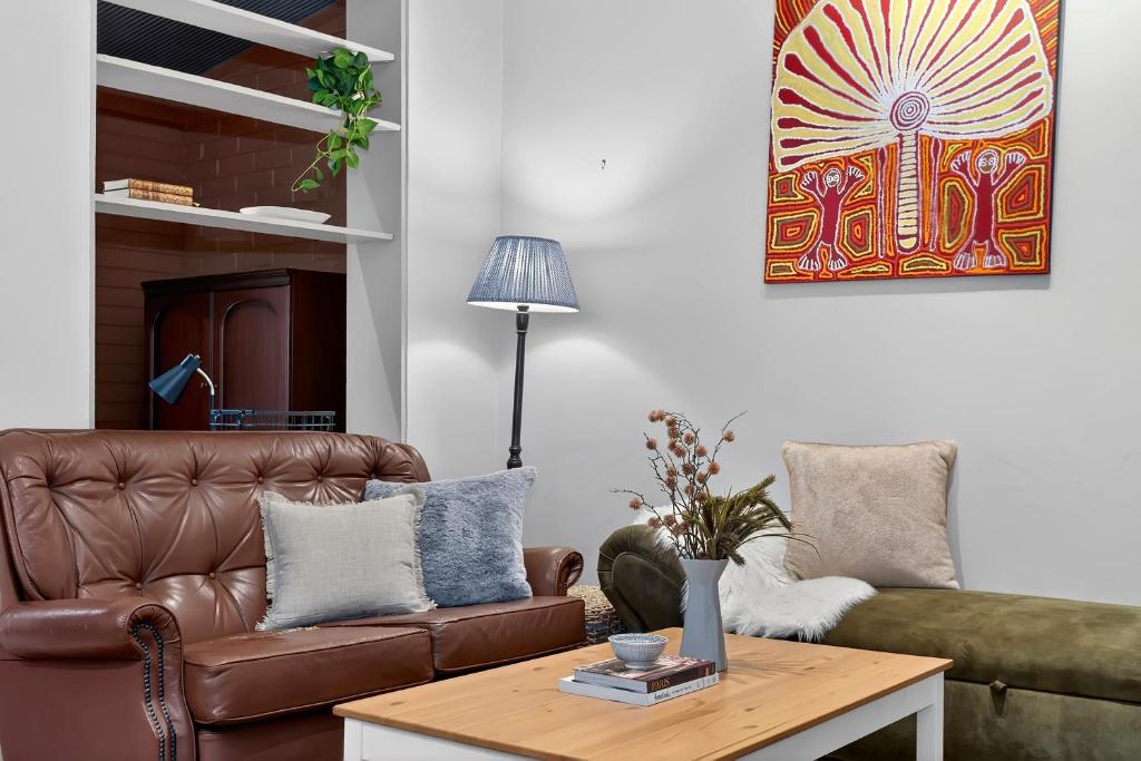 a living room with a brown leather couch and a coffee table at Ada Art Deco by Host Solutions Hutt St, Heritage in Adelaide