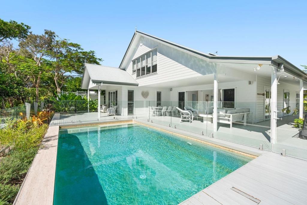 a swimming pool in front of a house at Winders Beach House in Marcoola