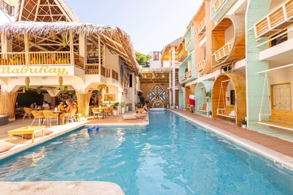 a swimming pool in a hotel with people sitting around it at Happiness Hostel Boracay in Boracay