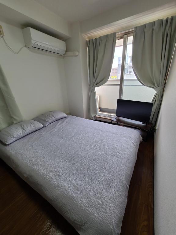 a small bedroom with a bed and a window at Namba Ebisu Tower701 in Osaka