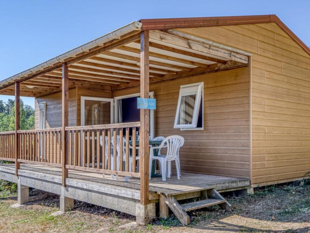 a cabin with a deck with two chairs and a table at Cottage, animaux acceptés - 6 pers. - API-1-52-2931 in Lamonzie-Montastruc