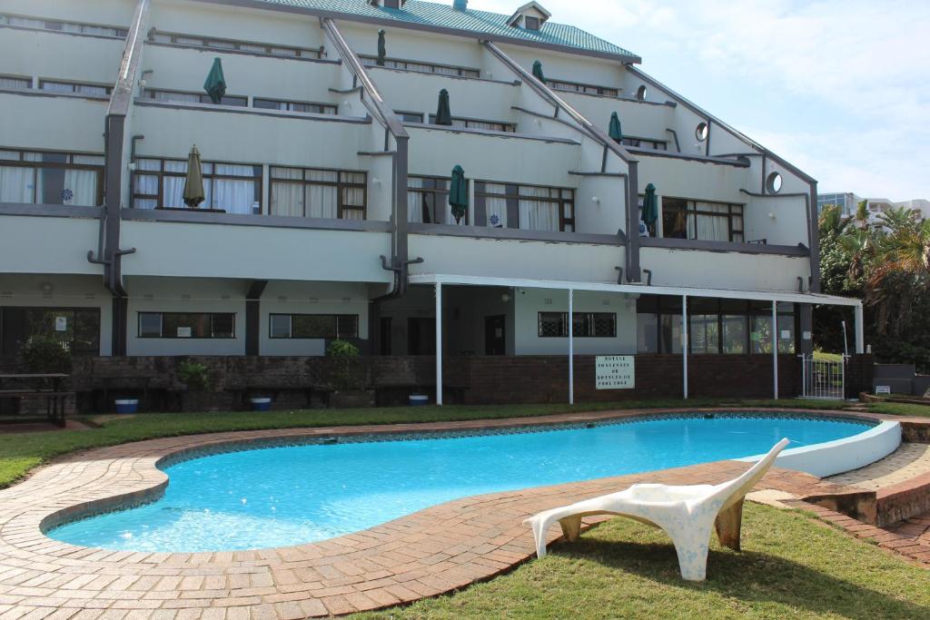 a hotel with a swimming pool in front of a building at Dumela Margate Flat No 4 in Margate