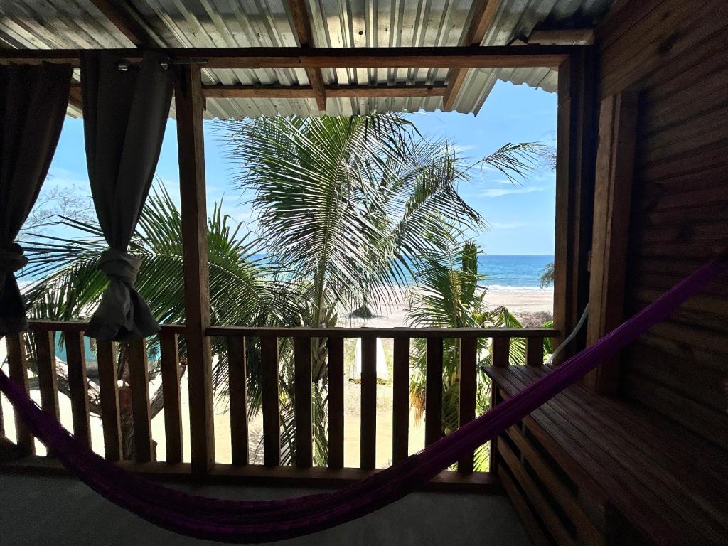 a hammock in a room with a view of the beach at Coco cabañas Tela in El Triunfo de la Cruz