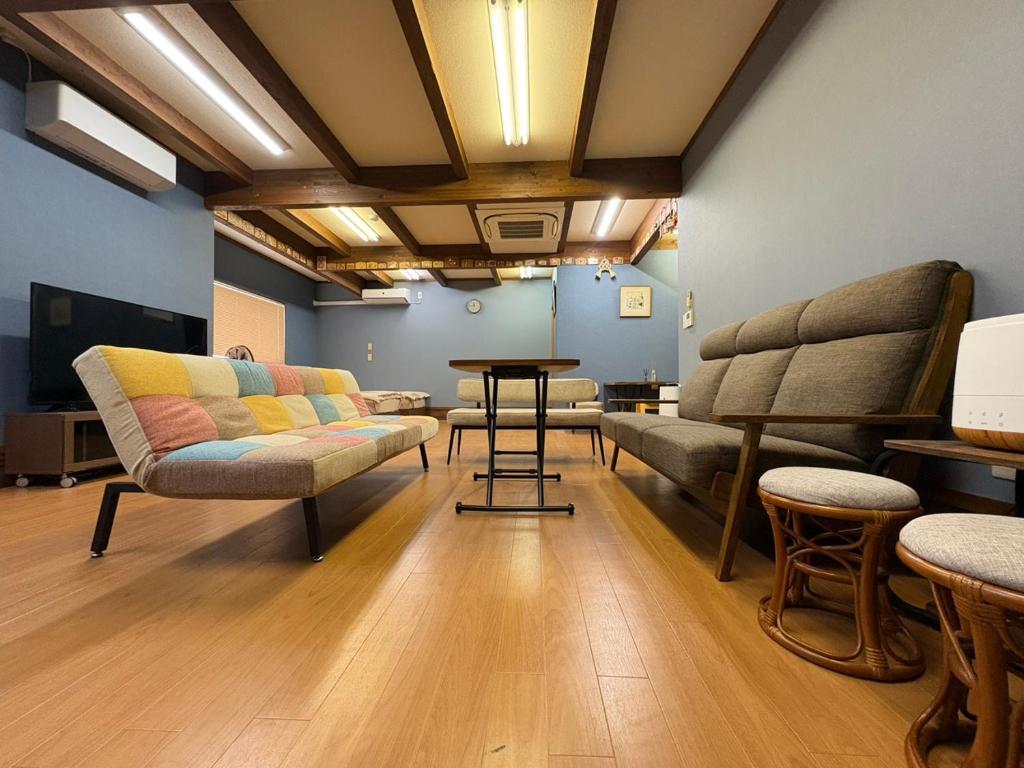 a room with two chairs and a table and a couch at Dons House in Fukuoka