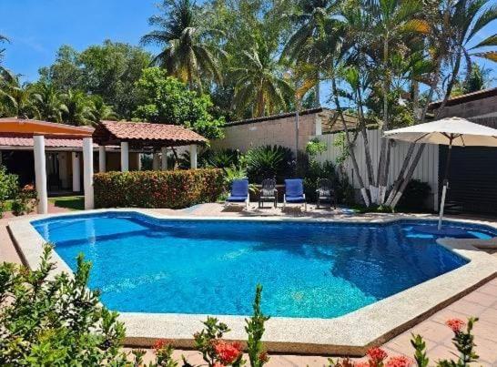a large blue swimming pool with chairs and an umbrella at Enjoy Cabo del Sol Costa del Sol in El Zapote