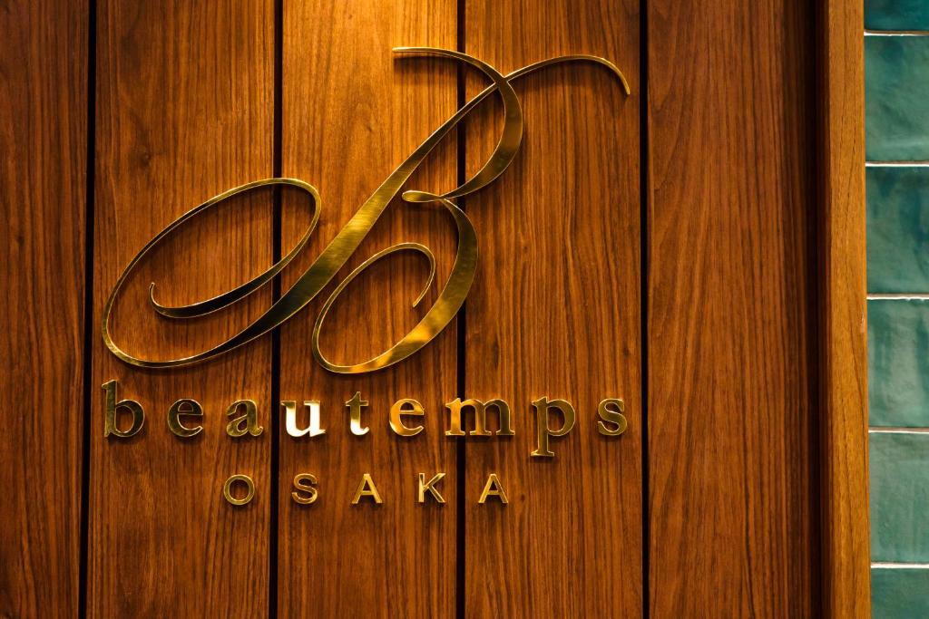 a wooden door with a sign for the entrance to a spa at Beautemps in Osaka