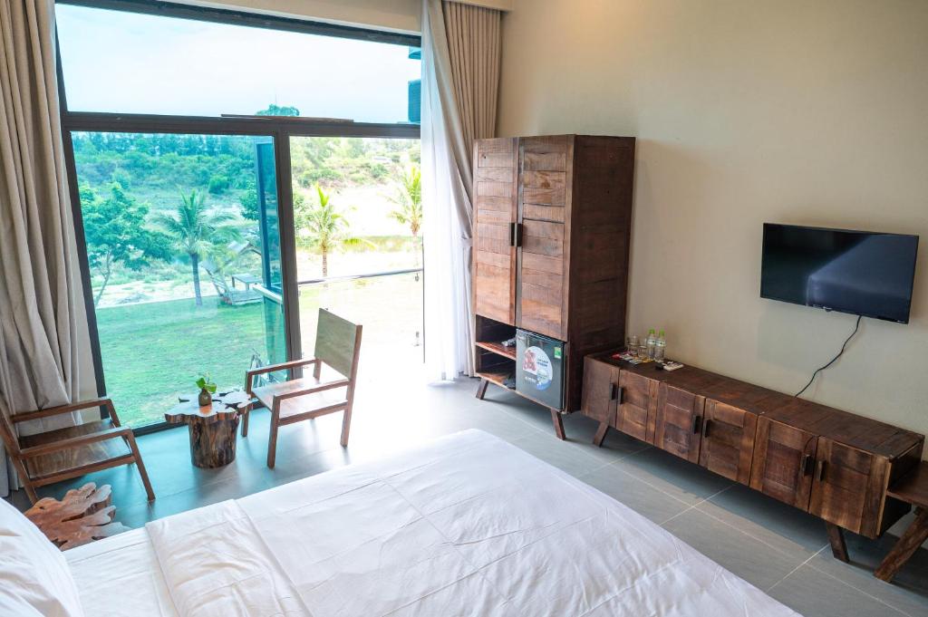 a bedroom with a bed and a tv and a large window at Lăng Cô Plaza in Thôn An Hảo