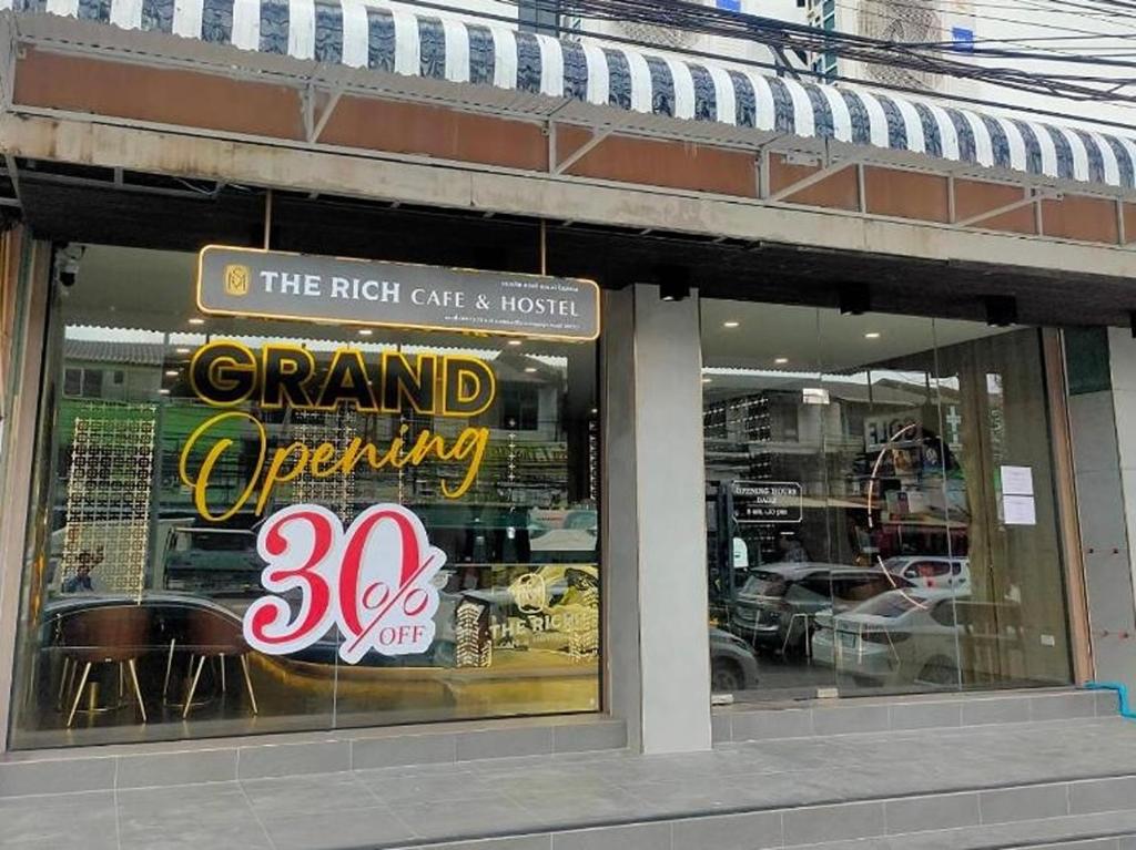 a grand opening sign in the window of a store at The Rich Cafe & Hostel in Pattaya South