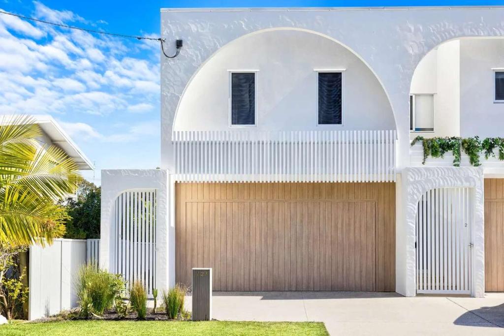 a white house with a brown garage at Key West Beach House in Coolum Beach