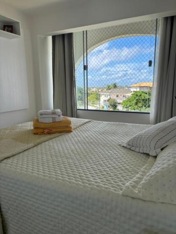 a bedroom with a white bed with a large window at Luxus Duplex 102m2 Vista Mar - Vilas do Atlântico in Lauro de Freitas