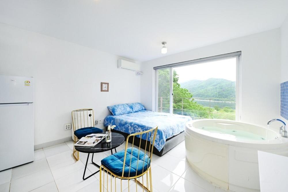 a bathroom with a tub and a bed and a table at Pygmalion Effect in Chuncheon