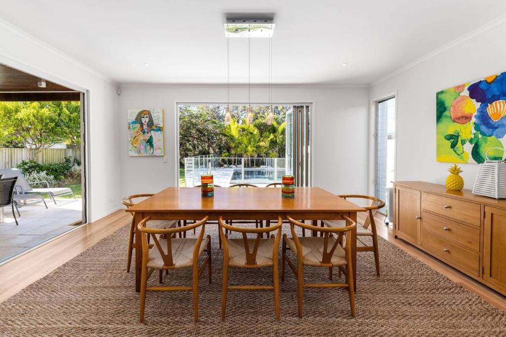 a dining room with a wooden table and chairs at Seaside Beach House in Marcoola