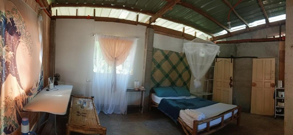 a small room with a bed and a window at Kalma Kubo Siargao in San Isidro