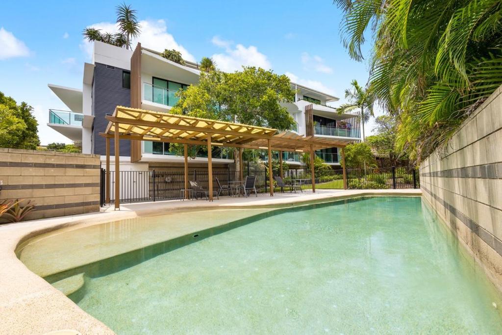 a swimming pool in front of a house at Peregian on the Beach Apt 1 in Peregian Beach