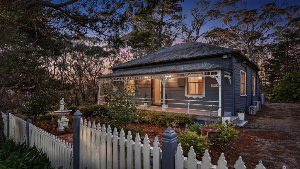 a small blue house in a yard with a fence at Le Petit Chateau in Medlow Bath