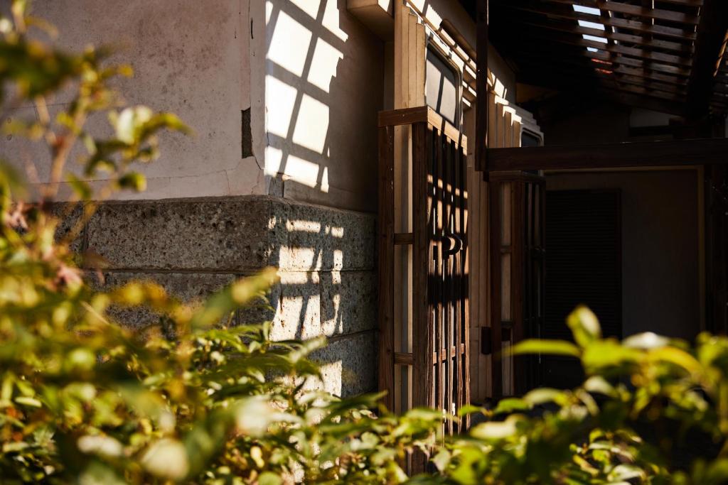 a shadow of a building with a window and a fence at 蔵宿あさぎやみたけ in Ome