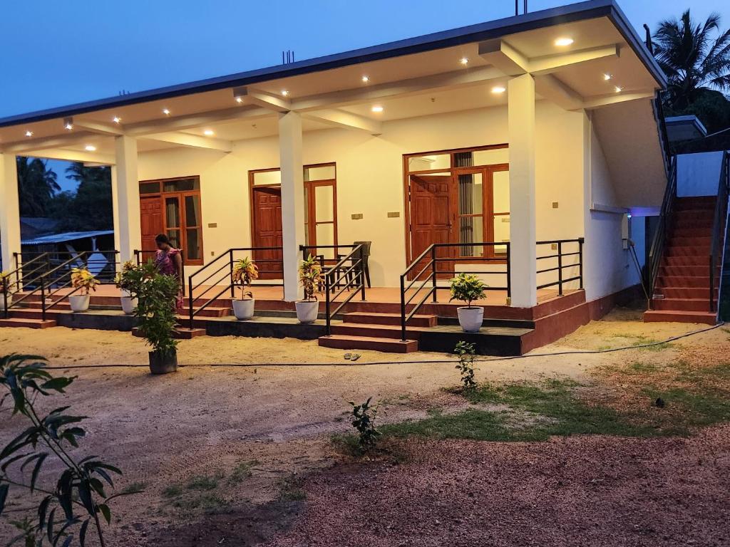 a house with a woman standing in front of it at Trinco salli beach resort in Trincomalee