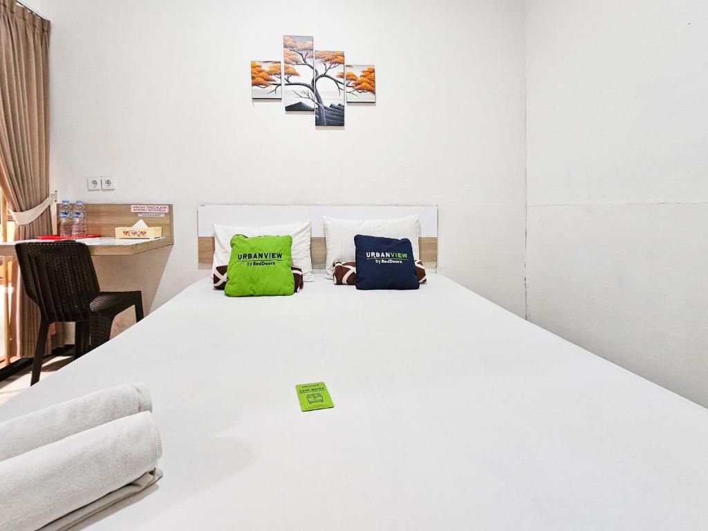 a white bed with two green pillows on it at Urbanview Java Living Sigura Gura in Betek