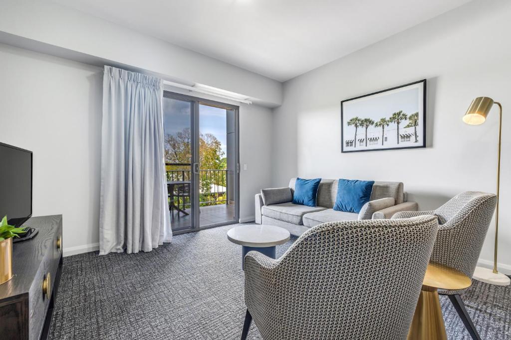 a living room with a couch and chairs and a tv at Hudson Parap in Darwin