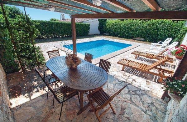a patio with a table and chairs and a swimming pool at Holiday Home Sandra in Sveti Lovreč Pazenatički