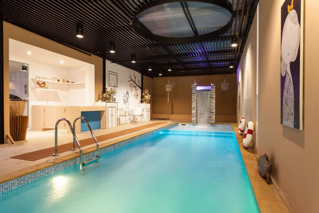 A bright indoor pool area with a ladder, seating nook and glass doors to the outside.